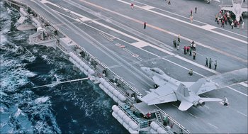 Movie still from “Aircraft Carrier: Guardian of the Seas” (2016), directed by Stephen Low – An aircraft is on the deck of an aircraft carrier; Extreme Wide shot, High angle