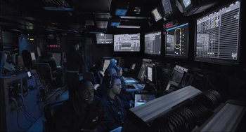 Movie still from “Aircraft Carrier: Guardian of the Seas” (2016), directed by Stephen Low – A group of people sitting in front of computer screens; Wide shot, High angle