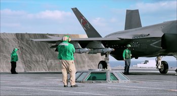 Movie still from “Aircraft Carrier: Guardian of the Seas” (2016), directed by Stephen Low – A man standing on the deck of an aircraft; Wide shot, Low angle