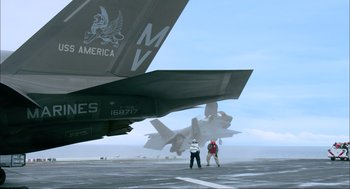 Movie still from “Aircraft Carrier: Guardian of the Seas” (2016), directed by Stephen Low – Two people standing in front of an airplane on a runway; Extreme Wide shot, Low angle