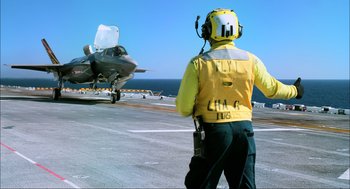 Movie still from “Aircraft Carrier: Guardian of the Seas” (2016), directed by Stephen Low – A man standing on the deck of an aircraft carrier; Wide shot, Low angle