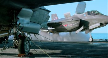 Movie still from “Aircraft Carrier: Guardian of the Seas” (2016), directed by Stephen Low – An airplane is on a runway with smoke billowing from it; Extreme Wide shot, Low angle