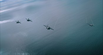 Movie still from “Aircraft Carrier: Guardian of the Seas” (2016), directed by Stephen Low – Two fighter jets flying over a body of water; Extreme Wide shot, High angle