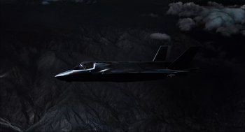 Movie still from “Aircraft Carrier: Guardian of the Seas” (2016), directed by Stephen Low – A fighter jet flying through the night sky; Extreme Wide shot, Overhead angle