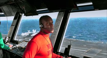 Movie still from “Aircraft Carrier: Guardian of the Seas” (2016), directed by Stephen Low – A man wearing a headset is in the cockpit of an aircraft; Medium shot, Low angle