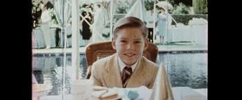 Movie still from “The Game” (1997), directed by David Fincher – A young boy in a suit and tie sitting at a table; Close Up shot, High angle