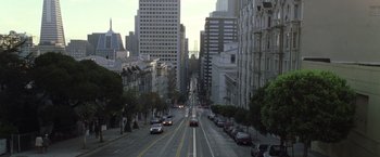 Movie still from “The Game” (1997), directed by David Fincher – A city street filled with lots of traffic and tall buildings on both sides of the street; Extreme Wide shot, High angle