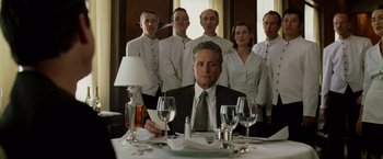 Movie still from “The Game” (1997), directed by David Fincher – A man sitting at a table with a group of people behind him; Medium shot, Low angle
