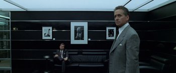 Movie still from “The Game” (1997), directed by David Fincher – Two men in suits sitting in front of a picture; Medium shot, Low angle
