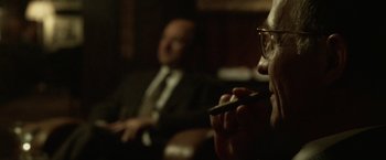 Movie still from “The Game” (1997), directed by David Fincher – A man with glasses is holding a cell phone in front of another man; Close Up shot, Over the shoulder angle