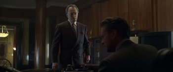 Movie still from “The Game” (1997), directed by David Fincher – A man in a suit standing next to another man in a suit and tie; Medium shot, Low angle