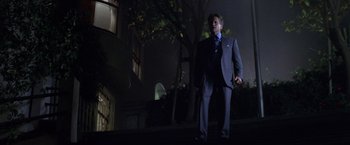 Movie still from “The Game” (1997), directed by David Fincher – A man in a suit and tie standing on a sidewalk; Wide shot, Low angle
