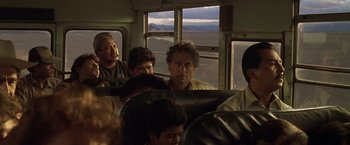 Movie still from “The Game” (1997), directed by David Fincher – A group of people riding on a bus with mountains in the background; Medium shot, Over the shoulder angle