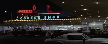 Movie still from “The Game” (1997), directed by David Fincher – Cars are parked in a parking lot in front of a coffee shop; Wide shot, Low angle