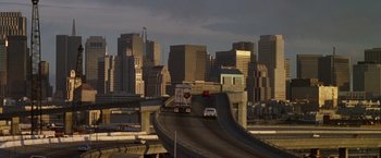 Movie still from “The Game” (1997), directed by David Fincher – A truck is driving down a highway in the middle of a city; Extreme Wide shot, High angle