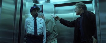 Movie still from “The Game” (1997), directed by David Fincher – A man pointing a gun at another man in uniform; Medium shot, Low angle