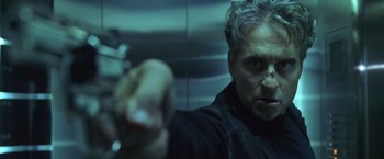 Movie still from “The Game” (1997), directed by David Fincher – A man in a black jacket holding a gun; Close Up shot, Low angle