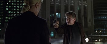 Movie still from “The Game” (1997), directed by David Fincher – A man holding a gun pointed at another man in front of a building at night; Close Up shot, Over the shoulder angle