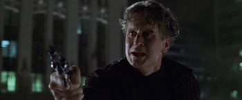 Movie still from “The Game” (1997), directed by David Fincher – An older man in a black shirt is holding something in his hand; Close Up shot, Over the shoulder angle