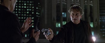 Movie still from “The Game” (1997), directed by David Fincher – A man holding two guns in his hands; Close Up shot, Over the shoulder angle