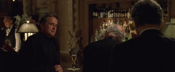 Movie still from “The Game” (1997), directed by David Fincher – A man sitting at a table in front of a glass of wine; Medium shot, Over the shoulder angle