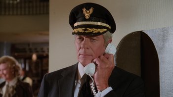 Movie still from “Airplane!” (1980), directed by David Zucker – An older man in a suit and hat talking on a phone; Close Up shot, Low angle