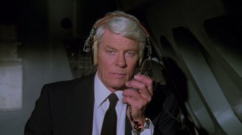 Movie still from “Airplane!” (1980), directed by David Zucker – An older man wearing headphones while talking on a cell phone; Close Up shot, Low angle