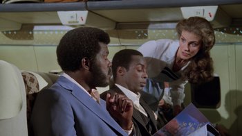 Movie still from “Airplane!” (1980), directed by David Zucker – A group of men and a woman sitting next to each other on a train; Medium shot, Low angle