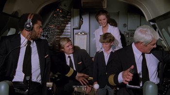 Movie still from “Airplane!” (1980), directed by David Zucker – A group of men and women standing in a room; Medium shot, High angle
