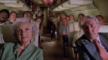 Movie still from “Airplane!” (1980), directed by David Zucker – A group of people sitting on a train car; Wide shot, Overhead angle