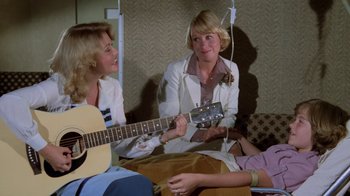 Movie still from “Airplane!” (1980), directed by David Zucker – A group of women sitting on a couch playing a guitar; Medium shot, High angle