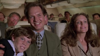 Movie still from “Airplane!” (1980), directed by David Zucker – A man and two children sitting on a plane; Medium shot, High angle
