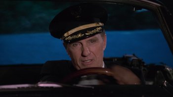 Movie still from “Airplane!” (1980), directed by David Zucker – A man in a military uniform sitting in a car; Close Up shot, Over the shoulder angle