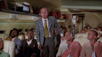 Movie still from “Airplane!” (1980), directed by David Zucker – A group of people sitting on a plane; Medium shot, Low angle