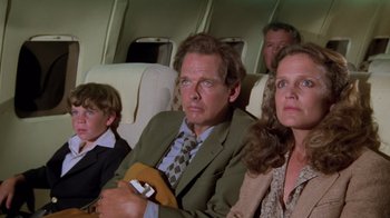 Movie still from “Airplane!” (1980), directed by David Zucker – A man and two women and a boy sitting on a plane; Medium shot, Low angle
