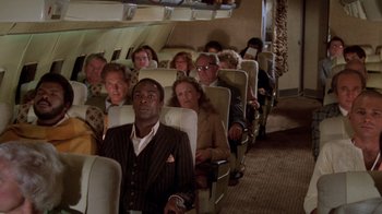 Movie still from “Airplane!” (1980), directed by David Zucker – A group of people sitting on a plane; Wide shot, High angle