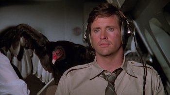 Movie still from “Airplane!” (1980), directed by David Zucker – A man with headphones and a bird in the background; Close Up shot, High angle