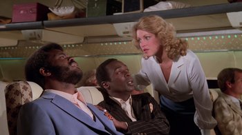 Movie still from “Airplane!” (1980), directed by David Zucker – A woman pointing at two men on a plane; Medium shot, Low angle