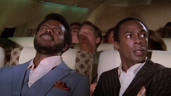 Movie still from “Airplane!” (1980), directed by David Zucker – A group of men sitting on a plane looking up at the sky; Close Up shot, Low angle