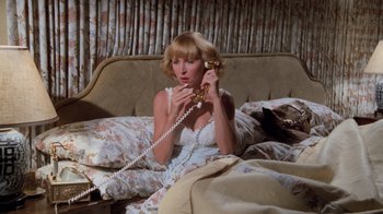 Movie still from “Airplane!” (1980), directed by David Zucker – A woman sitting on a bed talking on a phone; Medium shot, High angle