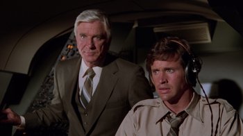 Movie still from “Airplane!” (1980), directed by David Zucker – A man and a man in a suit and tie; Medium shot, Low angle