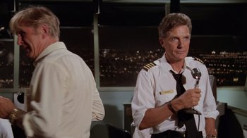 Movie still from “Airplane!” (1980), directed by David Zucker – A man in a white shirt and a black tie; Medium shot, Over the shoulder angle