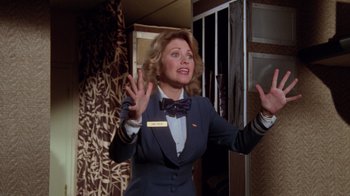 Movie still from “Airplane!” (1980), directed by David Zucker – A woman wearing a suit and a bow tie; Medium shot, Low angle
