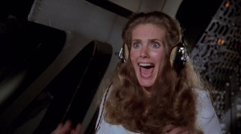 Movie still from “Airplane!” (1980), directed by David Zucker – A woman with long brown hair wearing headphones; Close Up shot, Overhead angle