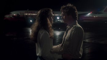 Movie still from “Airplane!” (1980), directed by David Zucker – A man and a woman standing next to each other in front of a bridge at night; Medium shot, Low angle