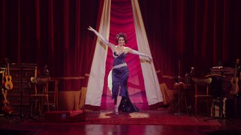 Movie still from “Alex Borstein: Corsets & Clown Suits” (2023), directed by Scott Ellis – A woman in a blue dress is performing a dance; Wide shot, Low angle