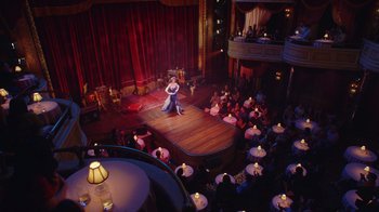 Movie still from “Alex Borstein: Corsets & Clown Suits” (2023), directed by Scott Ellis – A couple of people are dancing on a stage in front of a crowd of diners; Extreme Wide shot, High angle