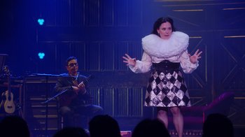 Movie still from “Alex Borstein: Corsets & Clown Suits” (2023), directed by Scott Ellis – A man and a woman on a stage singing; Medium shot, Over the shoulder angle
