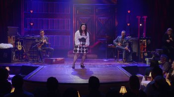Movie still from “Alex Borstein: Corsets & Clown Suits” (2023), directed by Scott Ellis – A group of people sitting on a stage; Wide shot, Over the shoulder angle