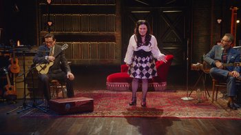 Movie still from “Alex Borstein: Corsets & Clown Suits” (2023), directed by Scott Ellis – A woman standing in front of a man on a stage; Wide shot, High angle